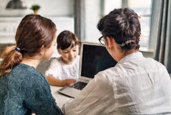 Photo of a family sitting infront of a laptop.
